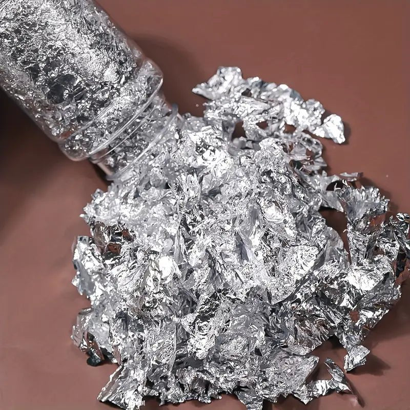 Silver foil flakes being poured from the jar for resin art